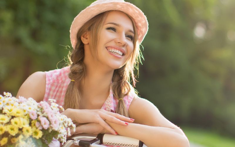Beautiful woman with great skin basking in the sunlight on her bicycle.
